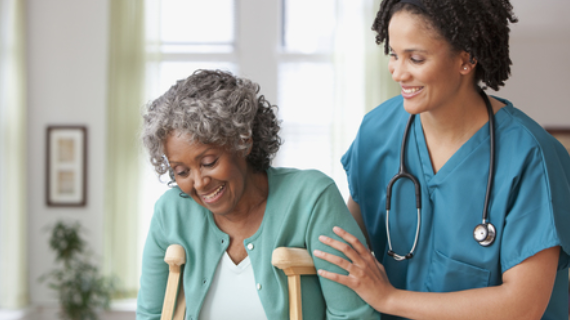A nurse helping an older woman move