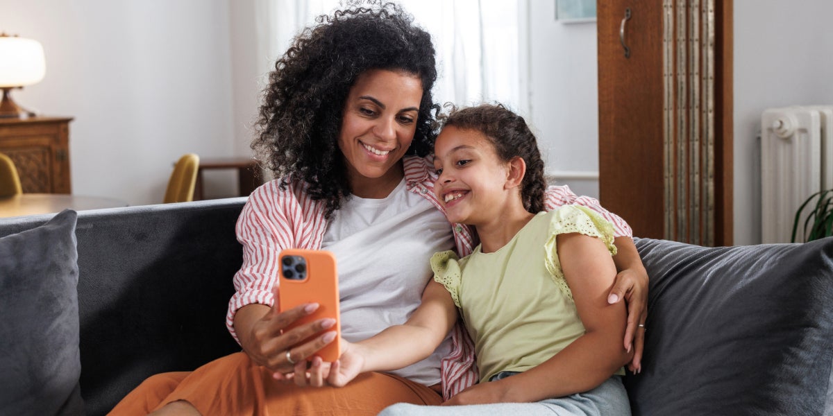 A mother and daughter look at a cell phone together.