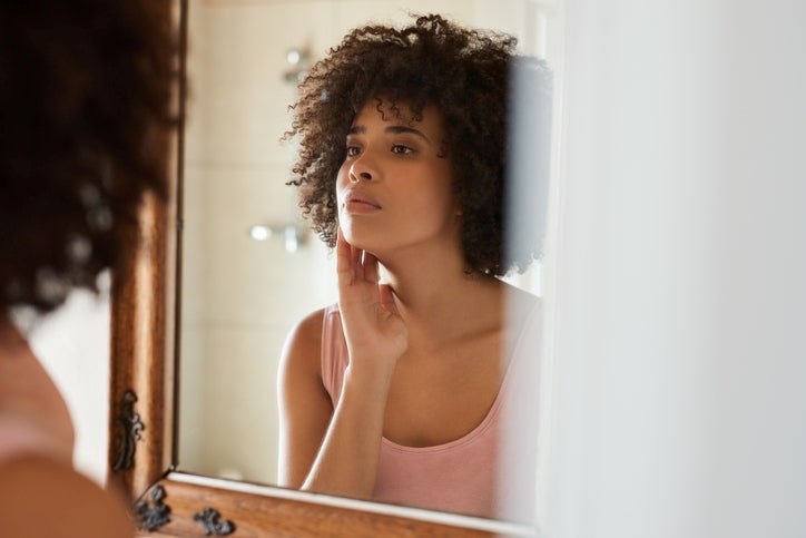 Woman looking in the mirror touching her face