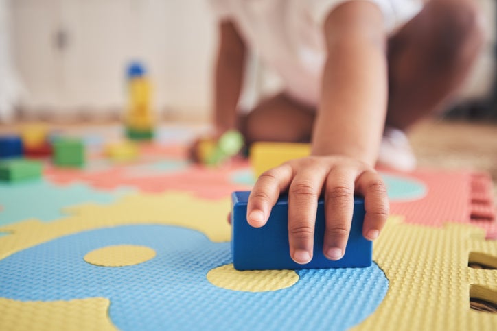 child's hand playing with block