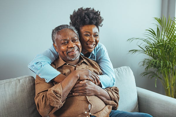 A woman hugs her father from behind his chair