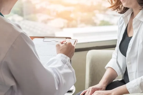 A zoomed in shot of a doctor holding a clipboard while she meets with a patient