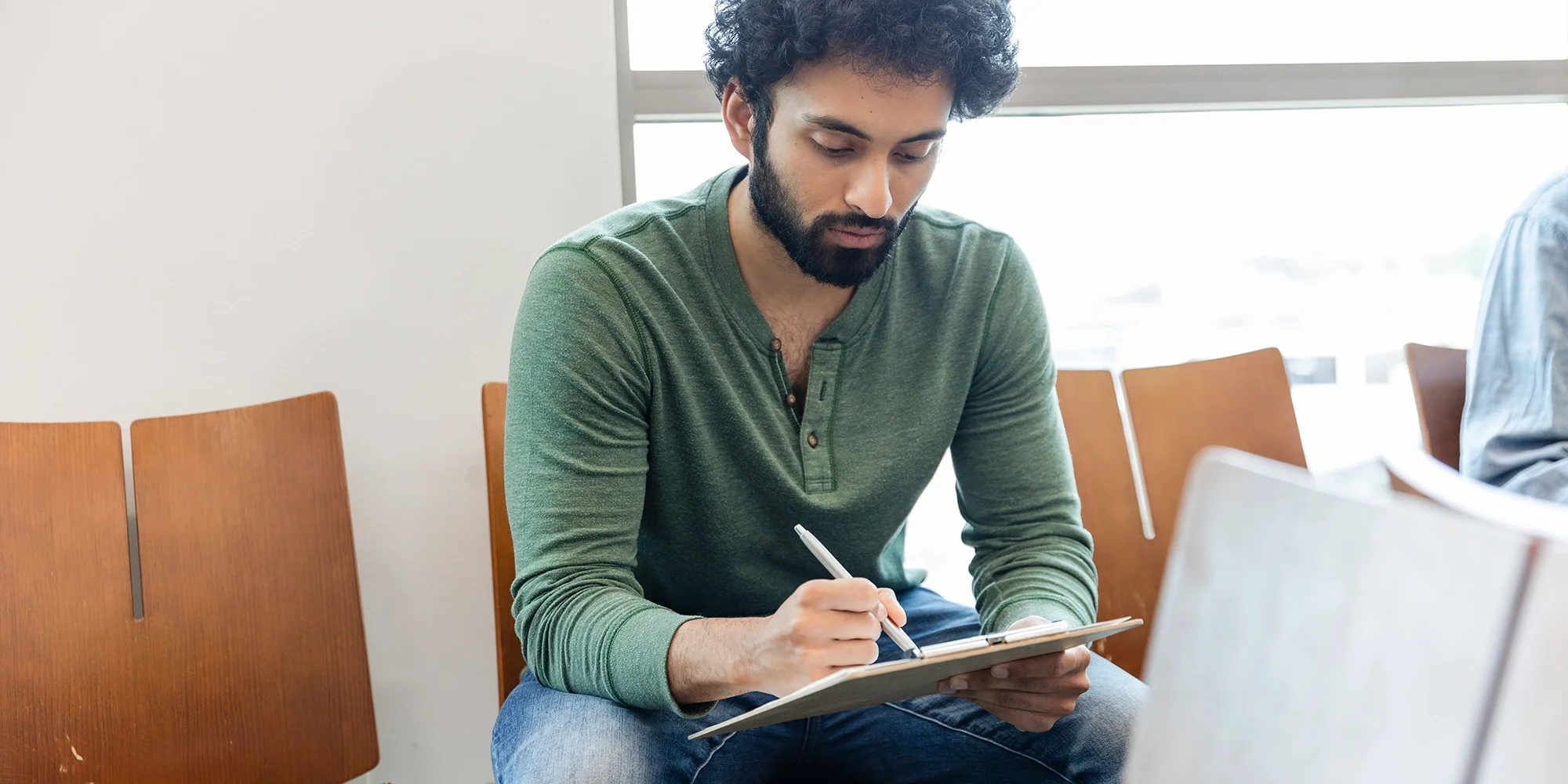 A man fills out paperwork in a doctor's office waiting room