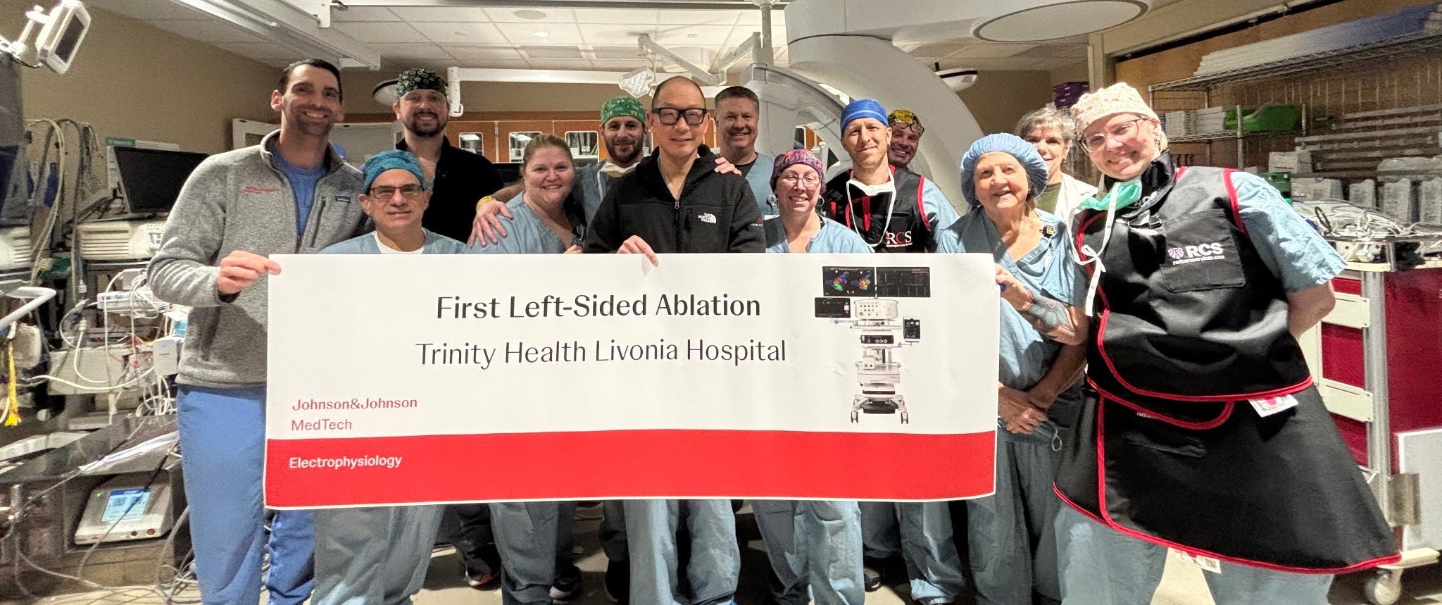 surgical team standing in operating room holding a banner about their accomplishment