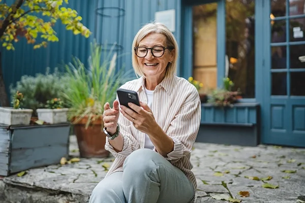 A woman uses her cell phone while sitting on a modern rustic porch