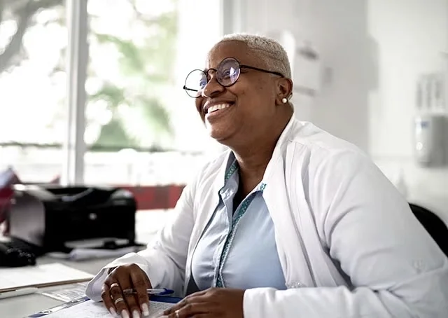 A doctor smiles while sitting at her desk