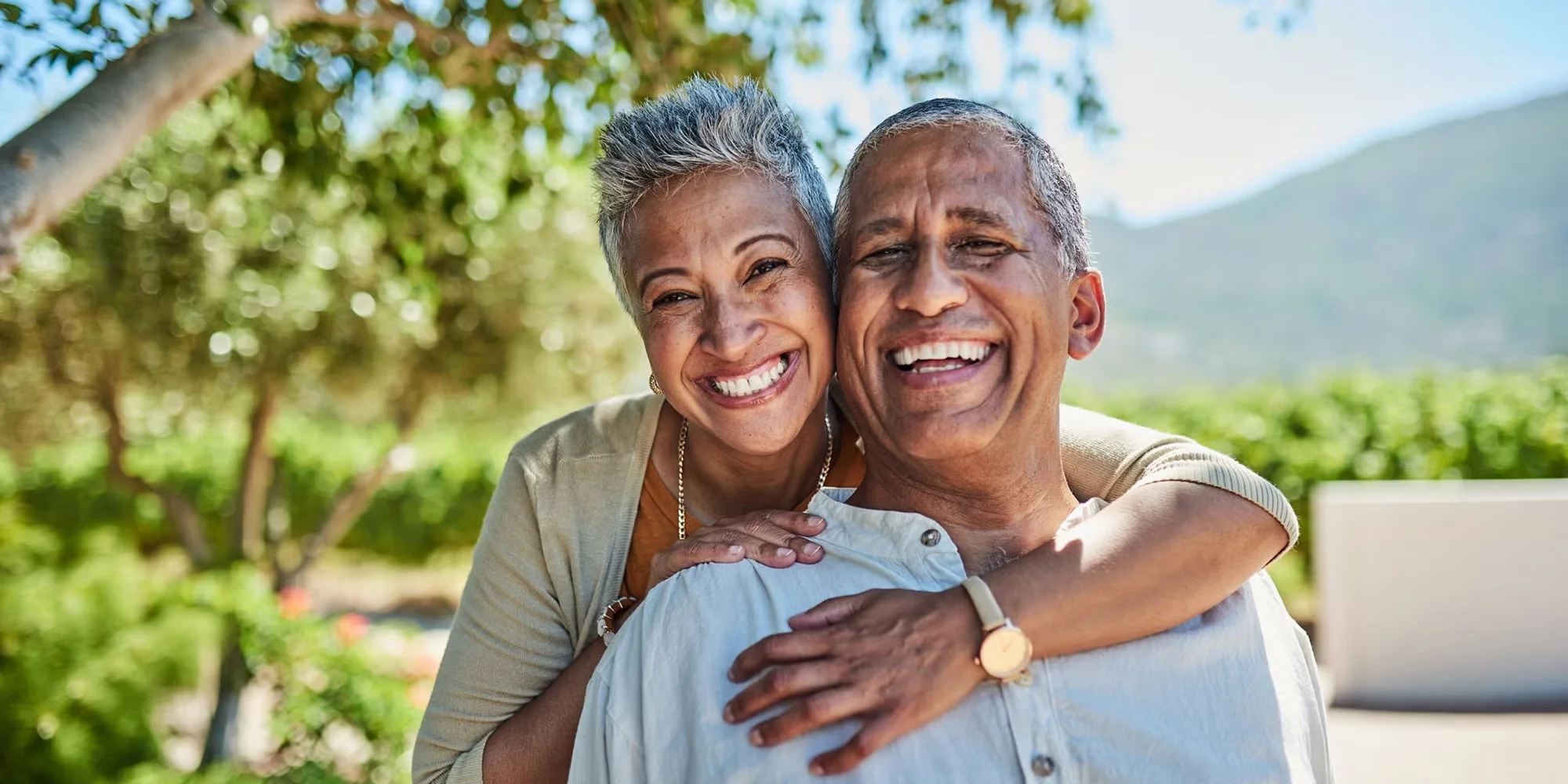 A smiling older couple glows in a garden