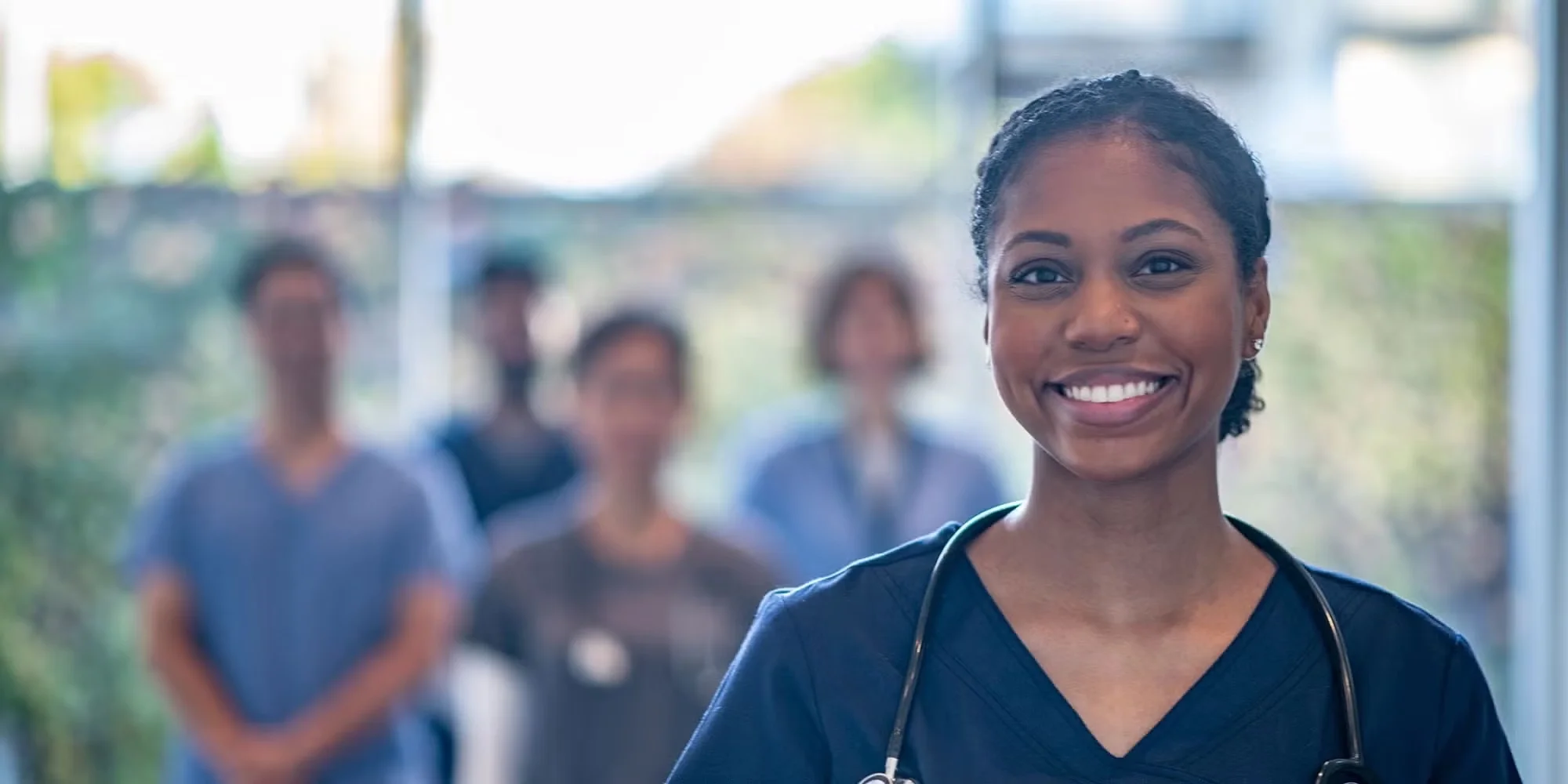 A group of medical residents stands in a hospital hallway smiling