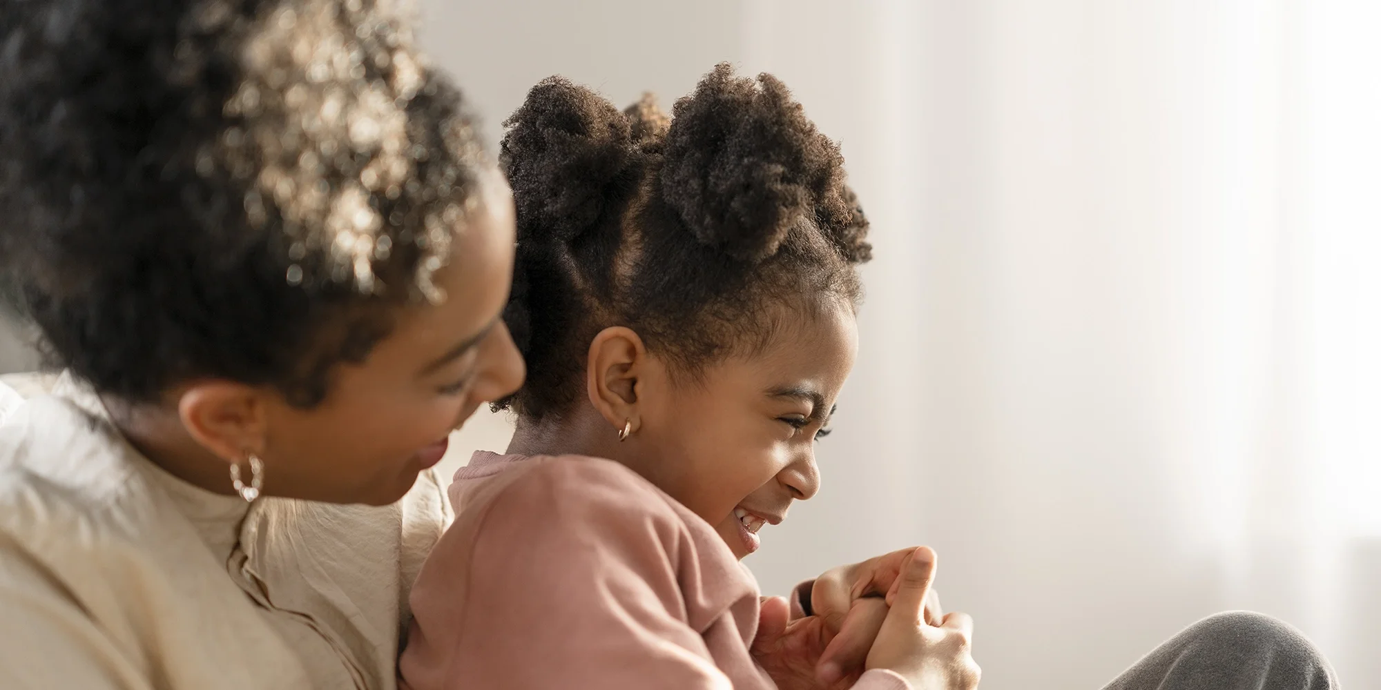 A mother cuddles her daughter inside their home