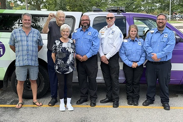 Trinity Health EMS colleagues stand in front of ambulance