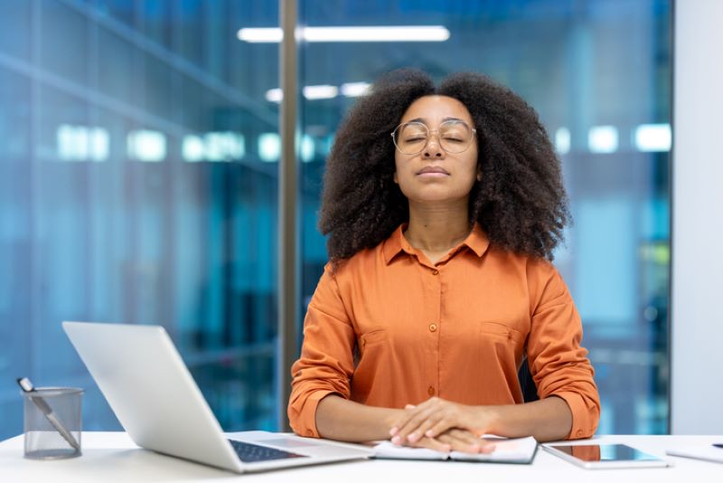 woman taking deep breath in front of laptop