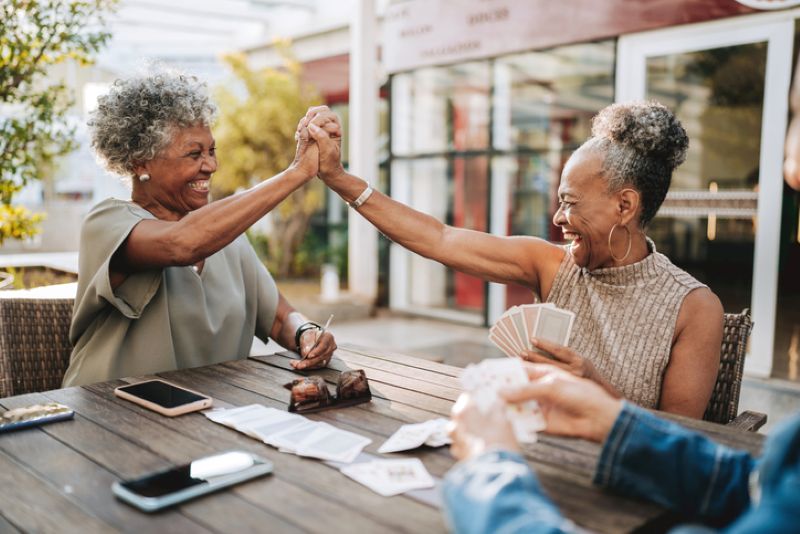 two retired women playing cards and high fiving