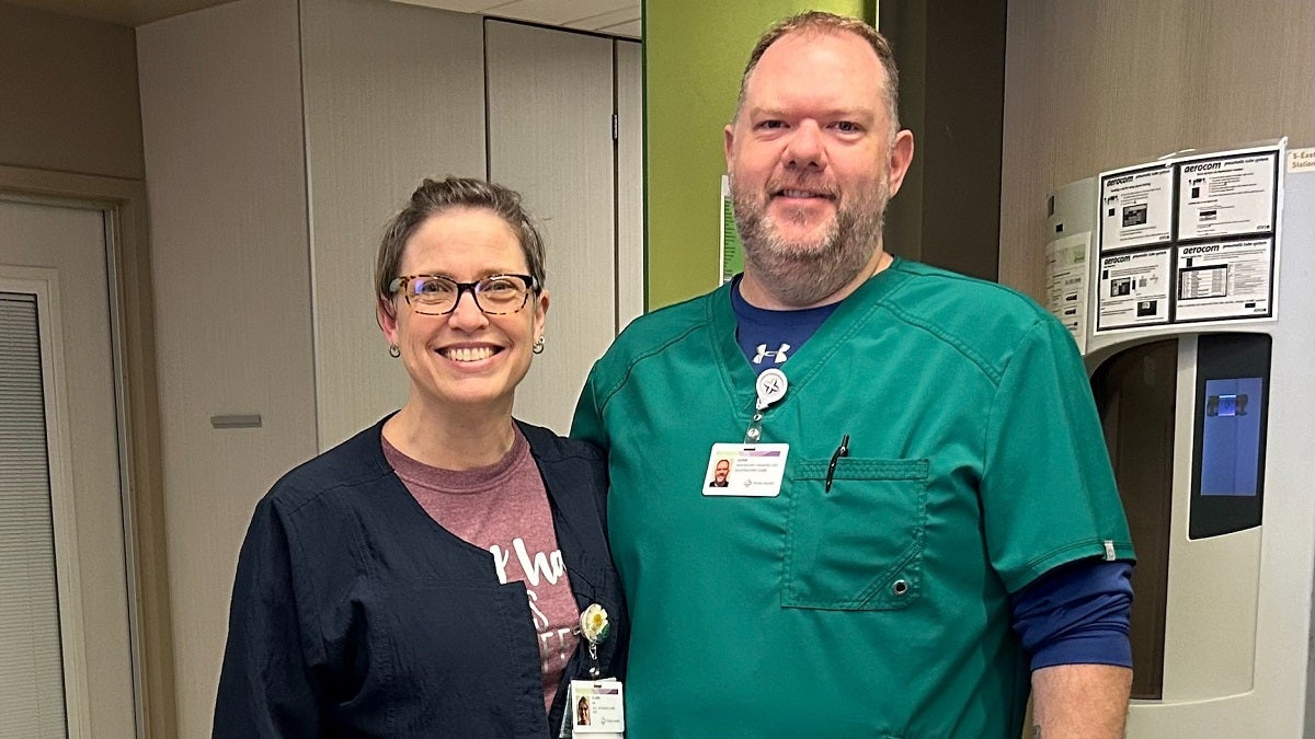Elaine and Adam standing together in their work uniforms