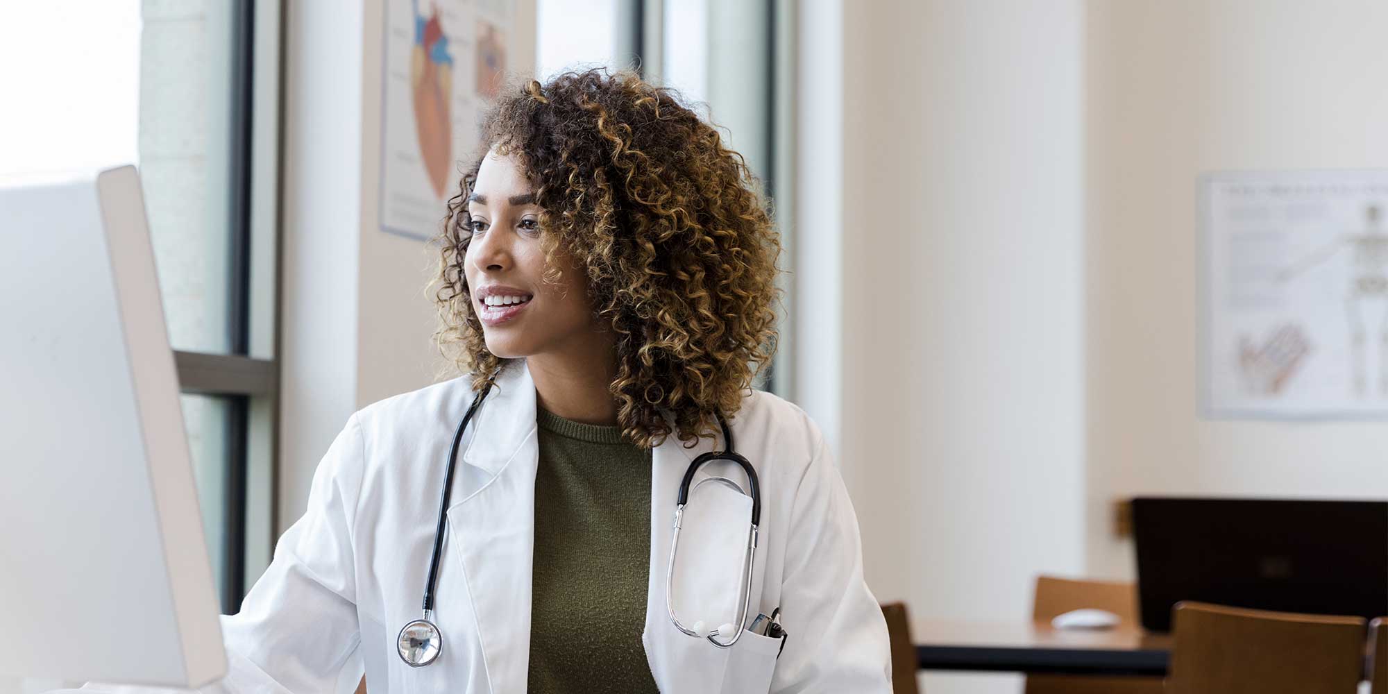 A doctor sits at a computer and conducts a video visit