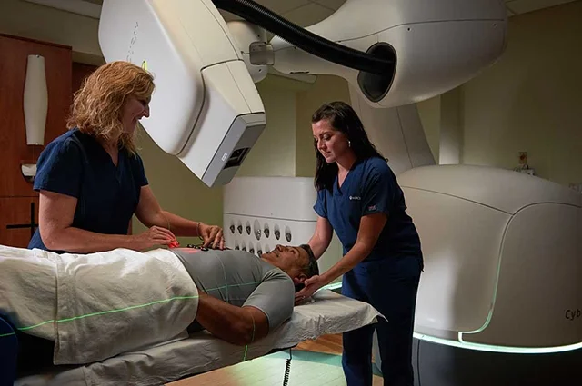 Two techs operating a Cyberknife machine on a cancer patient